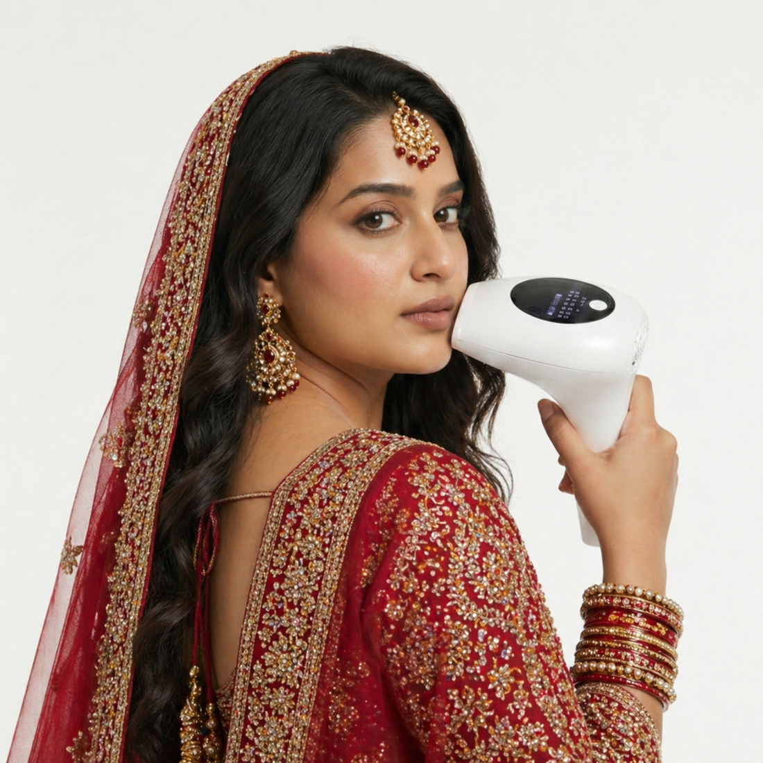 Pakistani bride in traditional red bridal wear using GlowPro IPL+ handset for facial hair removal on her cheek, jawline, chin, upper lip, face as part of her wedding prep.