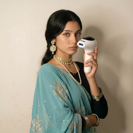 A Pakistani woman in elegant traditional teal attire holding the GlowPro IPL+ handset, highlighting it as a safe, clinically tested alternative to prevent laser burns and severe skin reactions.